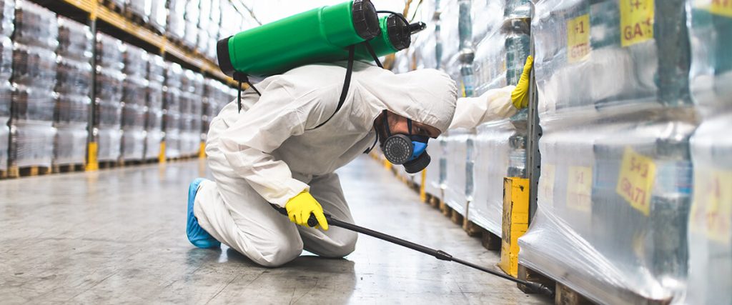 Person in white coveralls treating warehouse for pests